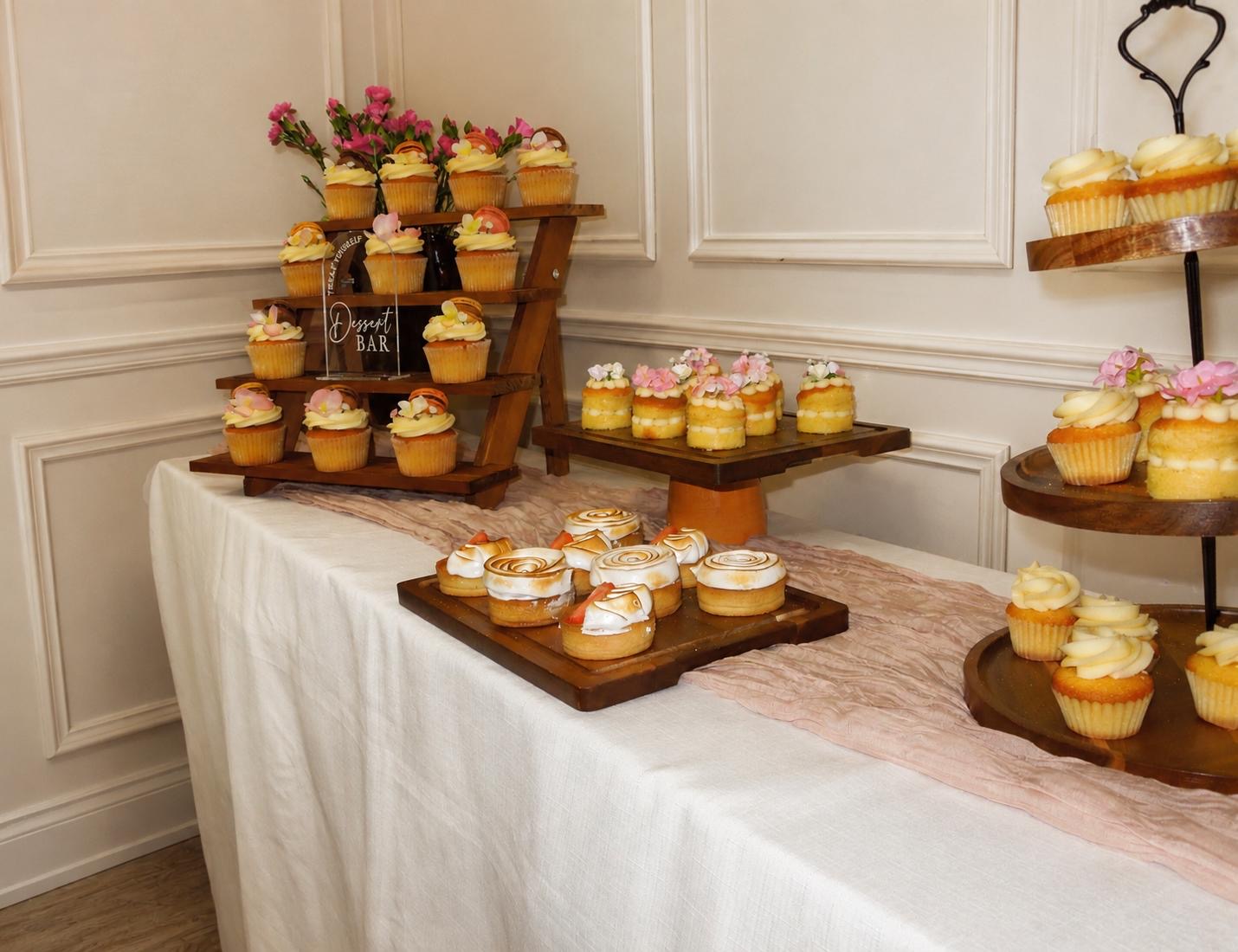 Dessert table of cupcakes, mini cakes and lemon meringue tartlets with florals
